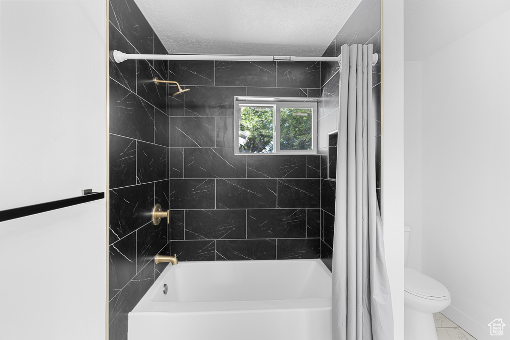 Full bath featuring shower / bath combination with curtain and a textured ceiling