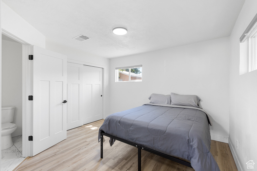 Bedroom with a closet, light wood-style floors, and ensuite bathroom