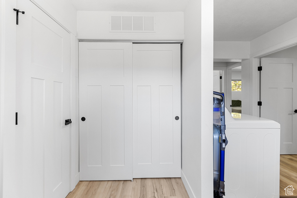 Corridor with washer / clothes dryer and light wood-style flooring