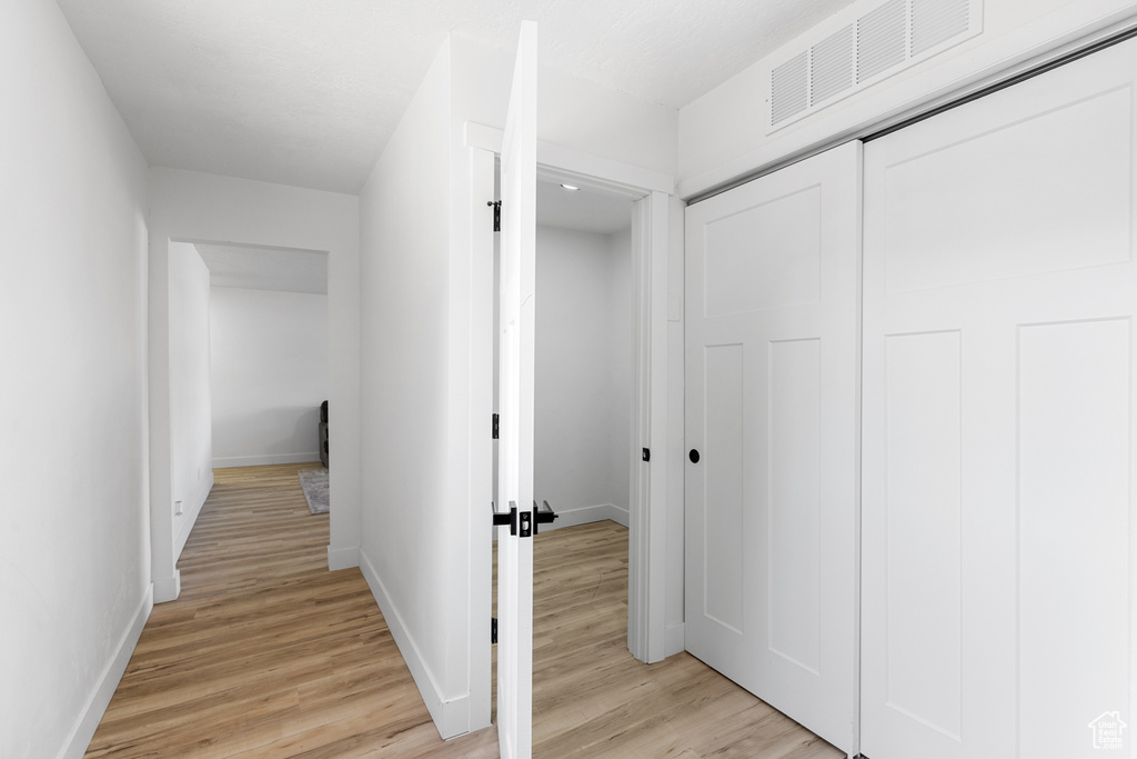 Hallway featuring light wood finished floors and baseboards