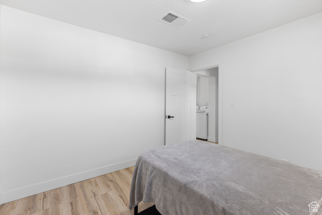 Bedroom with washer / dryer and light wood-style flooring