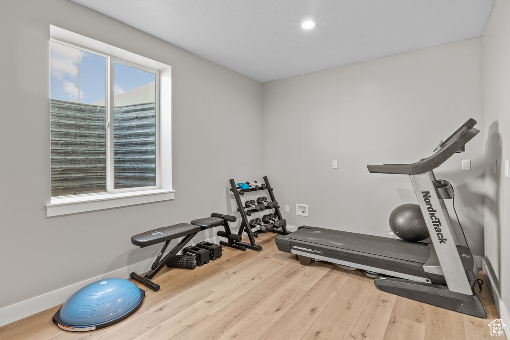 Exercise room with wood finished floors and recessed lighting