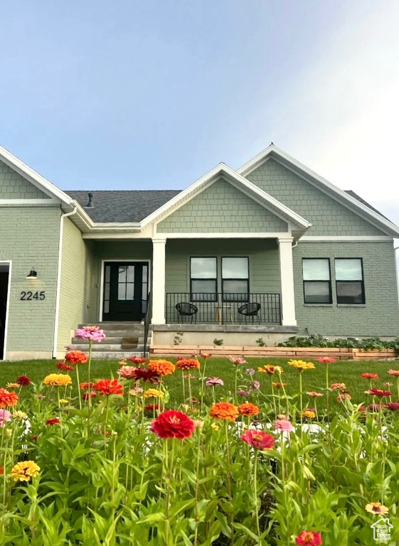 Back of house featuring a porch and brick siding