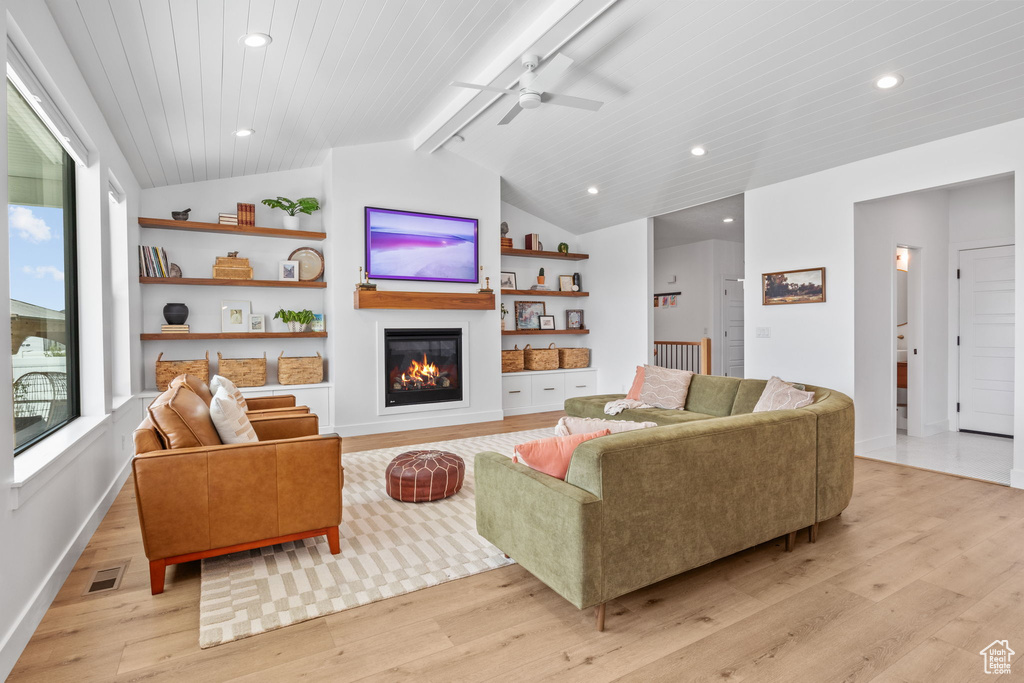 Living area featuring light wood-type flooring, a glass covered fireplace, ceiling fan, recessed lighting, and built in features