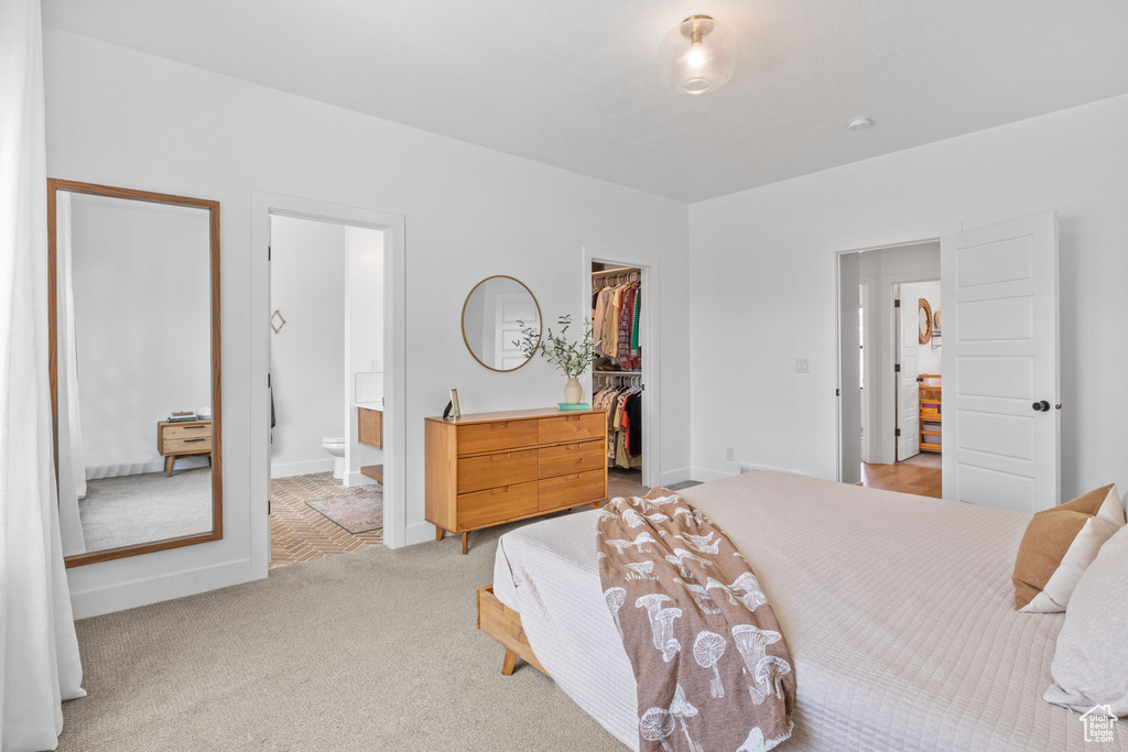 Carpeted bedroom featuring a walk in closet, a closet, and connected bathroom