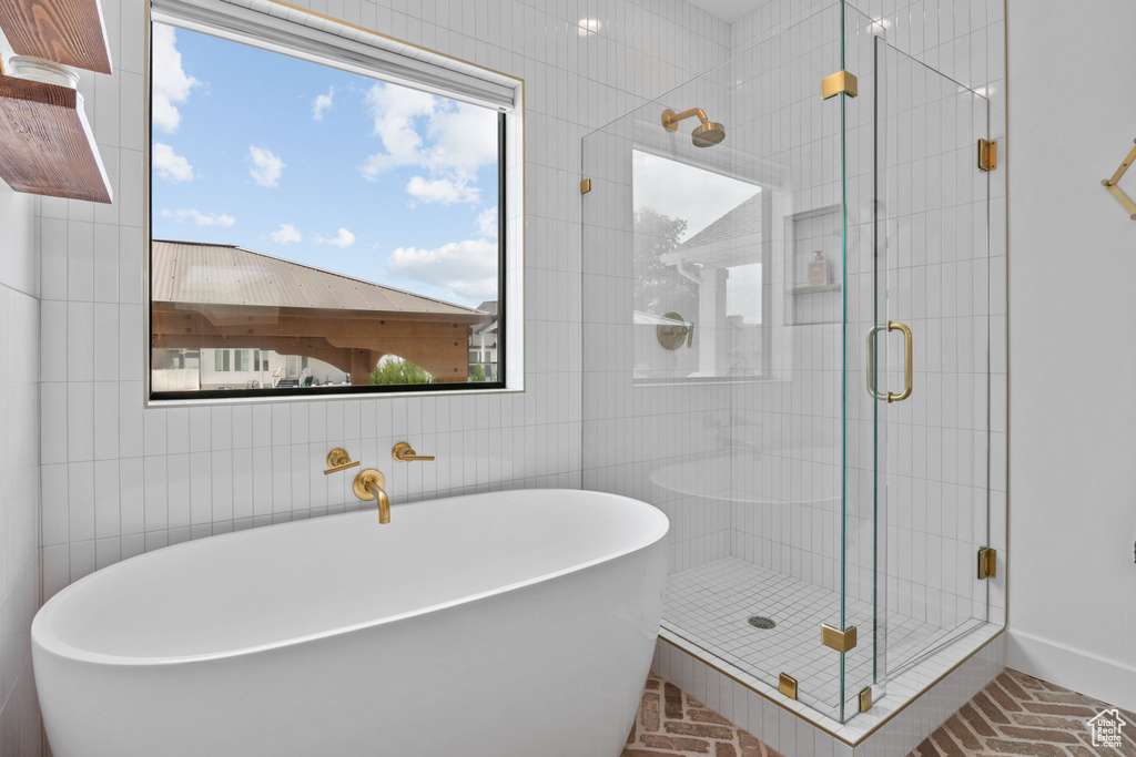 Full bath with a freestanding bath, a stall shower, plenty of natural light, and tile walls