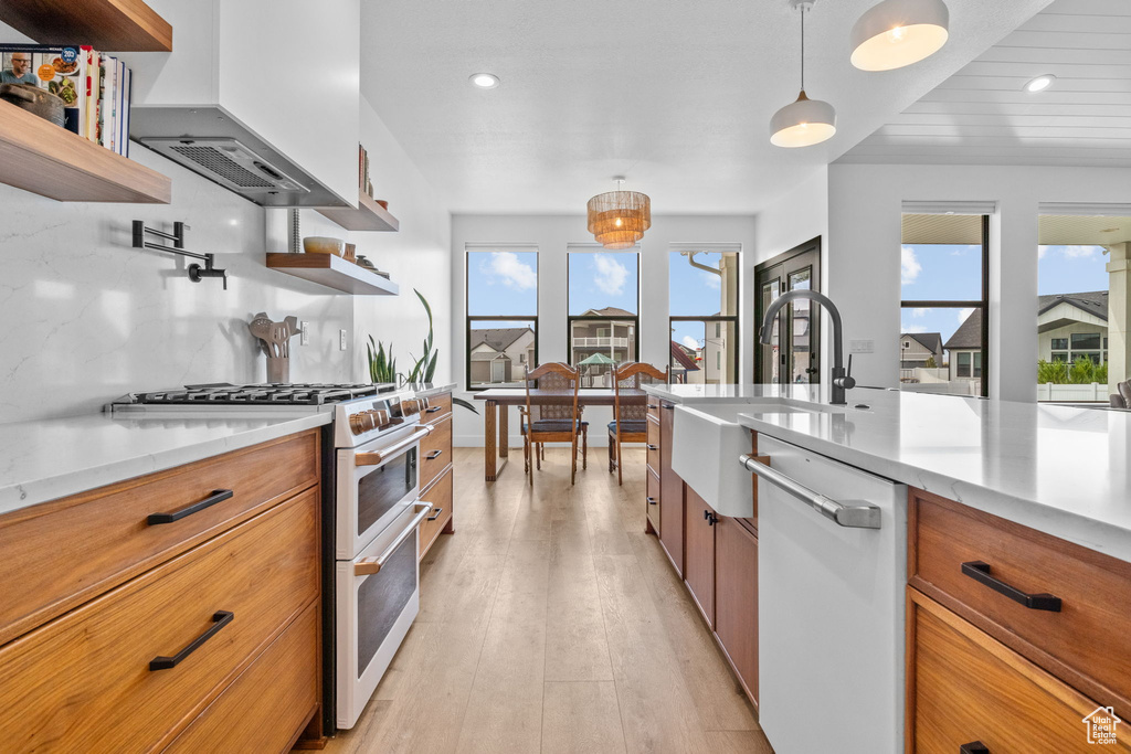 Kitchen with dishwasher, range with two ovens, open shelves, brown cabinetry, and recessed lighting