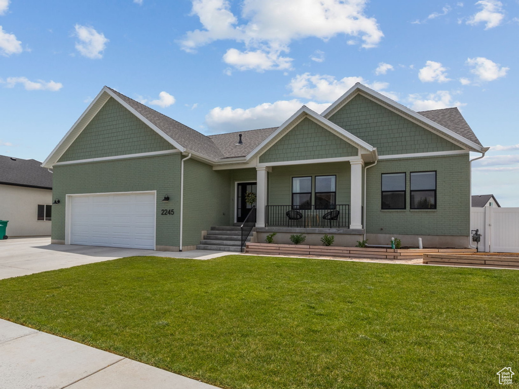 Craftsman inspired home featuring a porch, driveway, a front lawn, and a garage