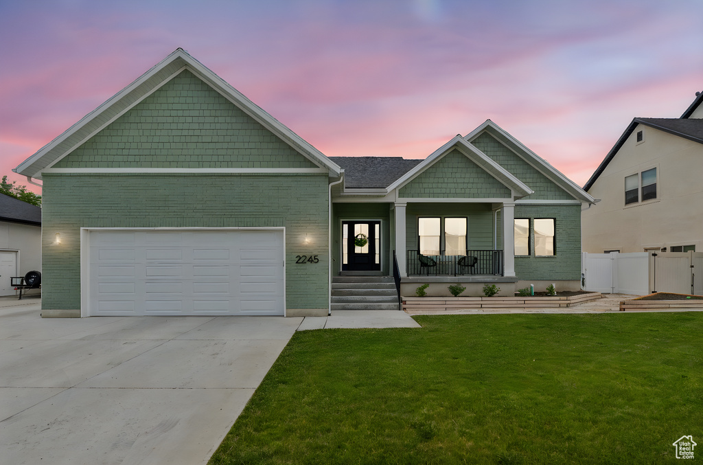 Craftsman-style house with a porch, driveway, brick siding, and an attached garage