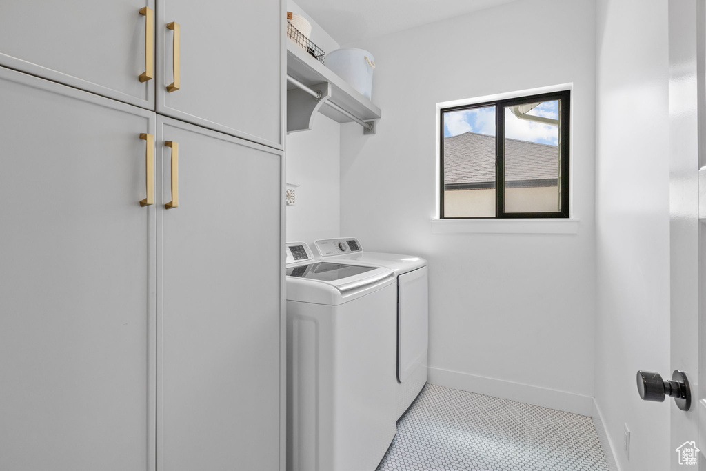 Washroom with washer and clothes dryer, cabinet space, and tile patterned flooring