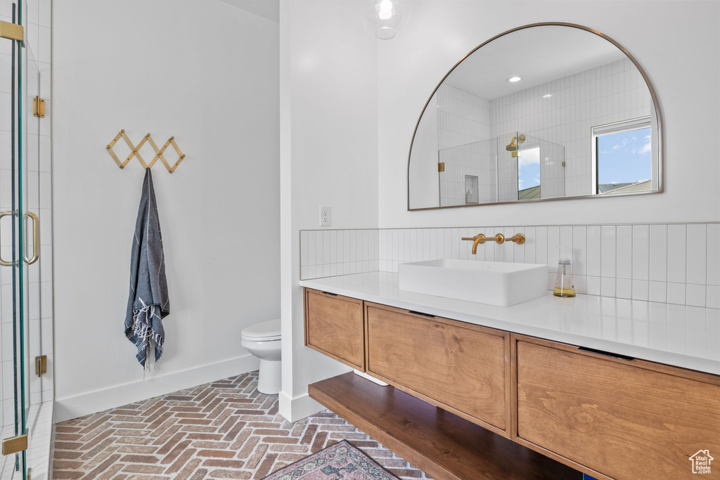 Full bathroom featuring brick flooring, vanity, and a stall shower