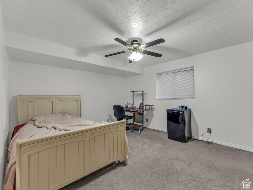 Bedroom featuring light colored carpet, a textured ceiling, and ceiling fan