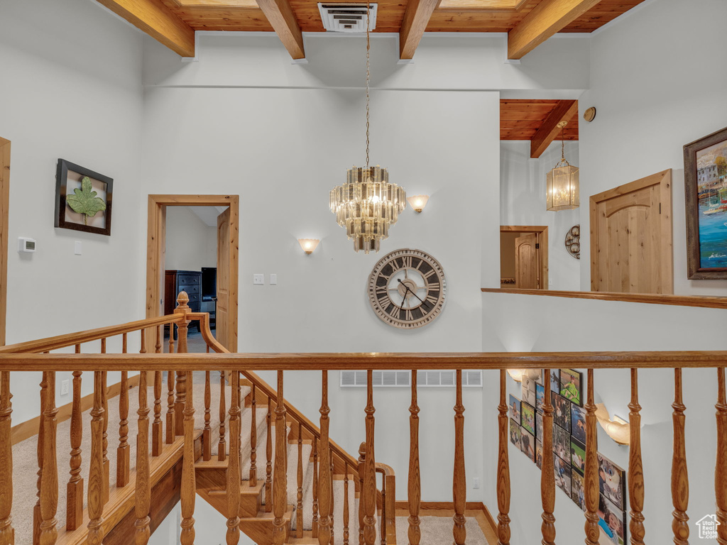 Hallway featuring a wood ceiling with exposed beams and a chandelier