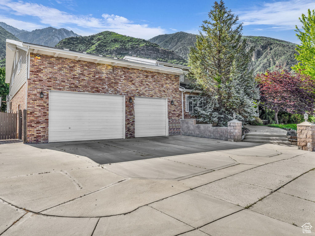 View of property exterior with a mountain view, driveway, and brick siding