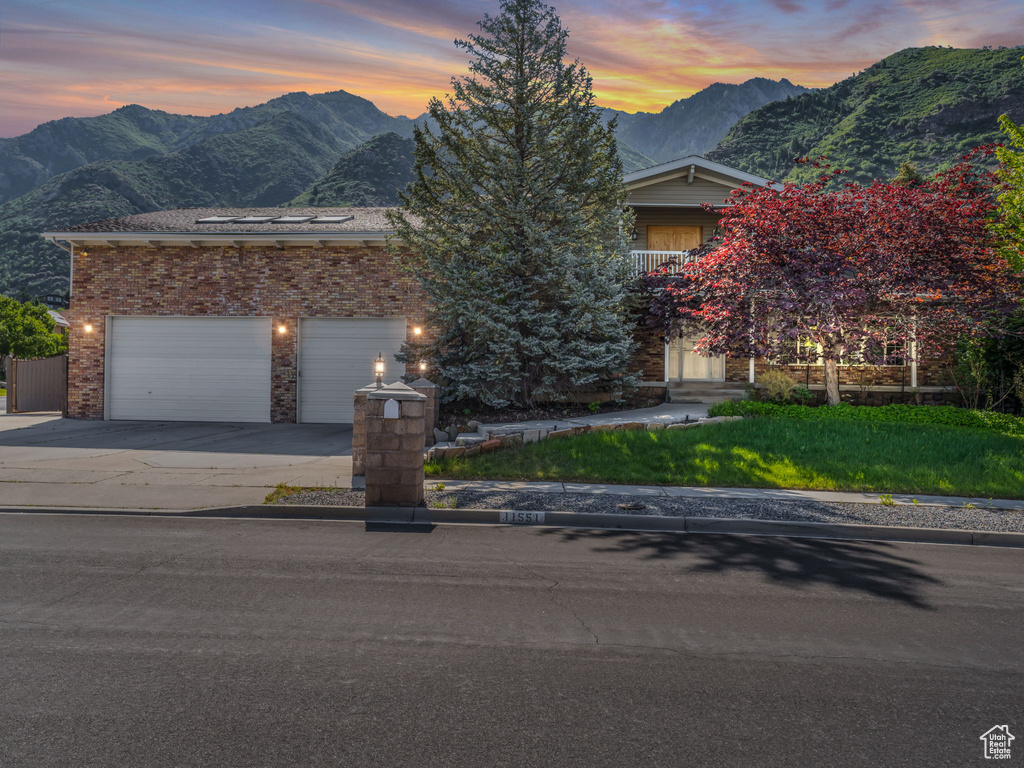 Obstructed view of property with a mountain view, concrete driveway, and brick siding