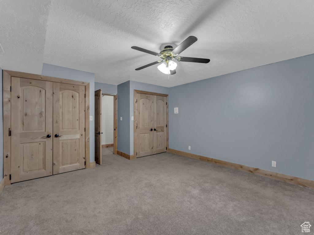 Unfurnished bedroom featuring carpet flooring, a textured ceiling, and ceiling fan