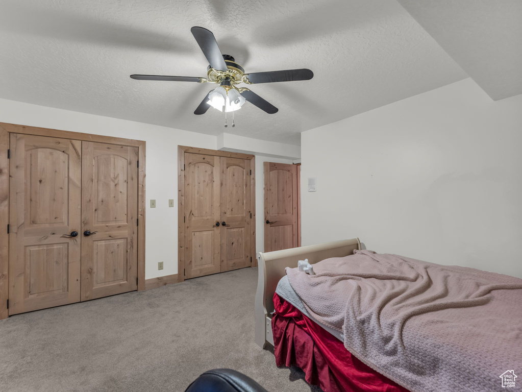 Bedroom featuring carpet floors, a ceiling fan, and a textured ceiling