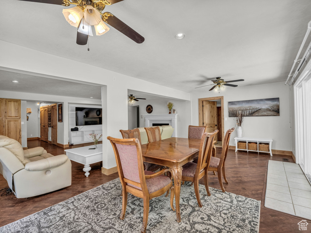 Dining area featuring a ceiling fan, a fireplace, wood finished floors, and recessed lighting