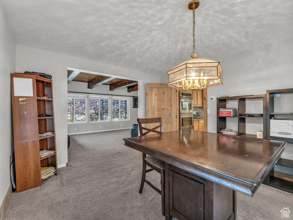Dining area with a chandelier, carpet, a textured ceiling, and beamed ceiling