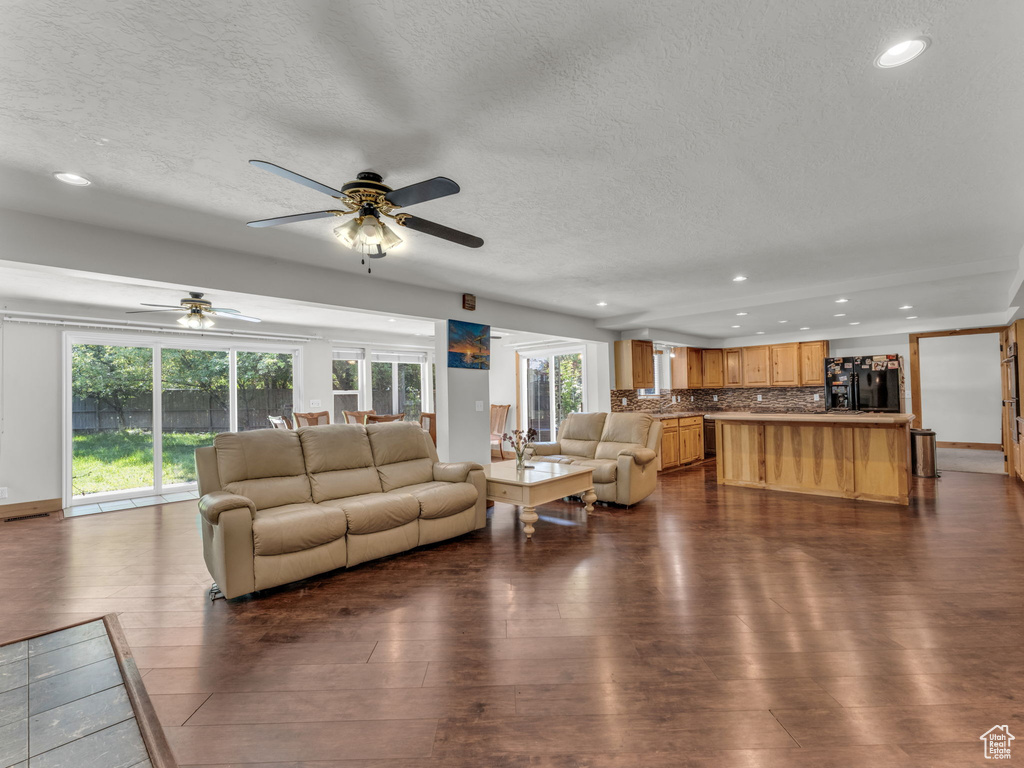 Living area with recessed lighting, a textured ceiling, a ceiling fan, and dark wood finished floors