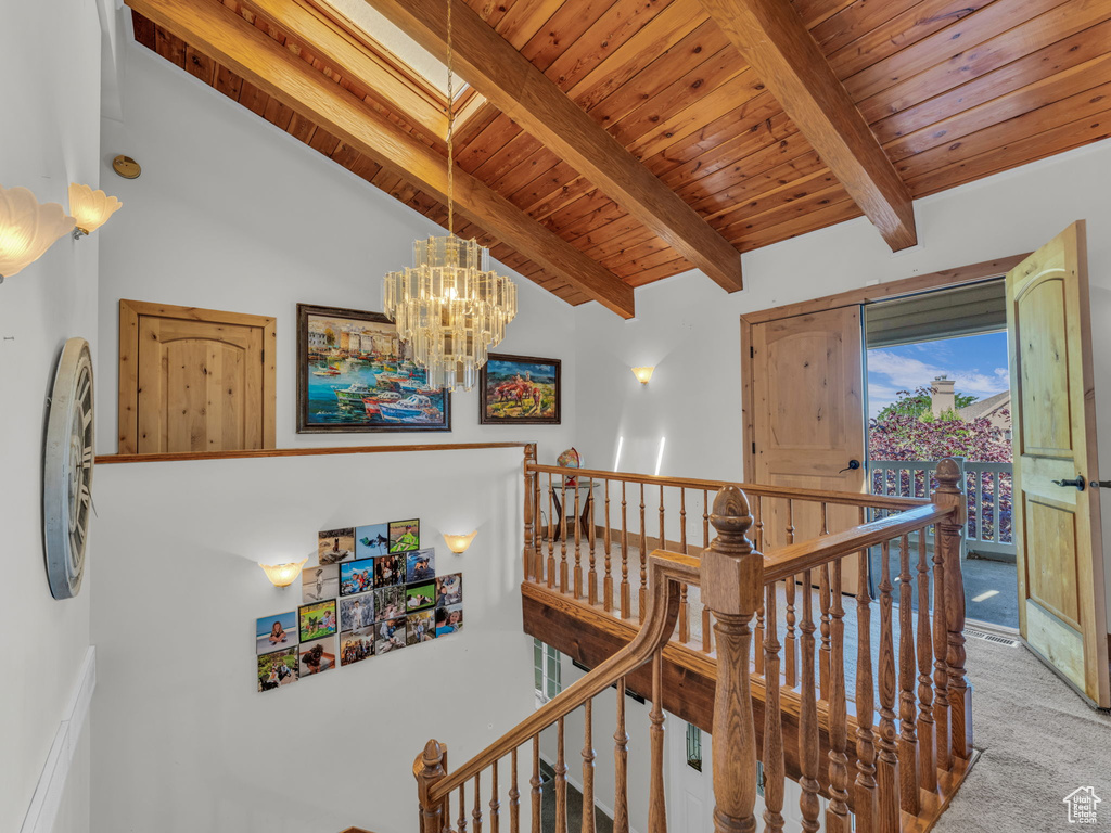 Corridor featuring an upstairs landing, wood ceiling, carpet flooring, and a chandelier