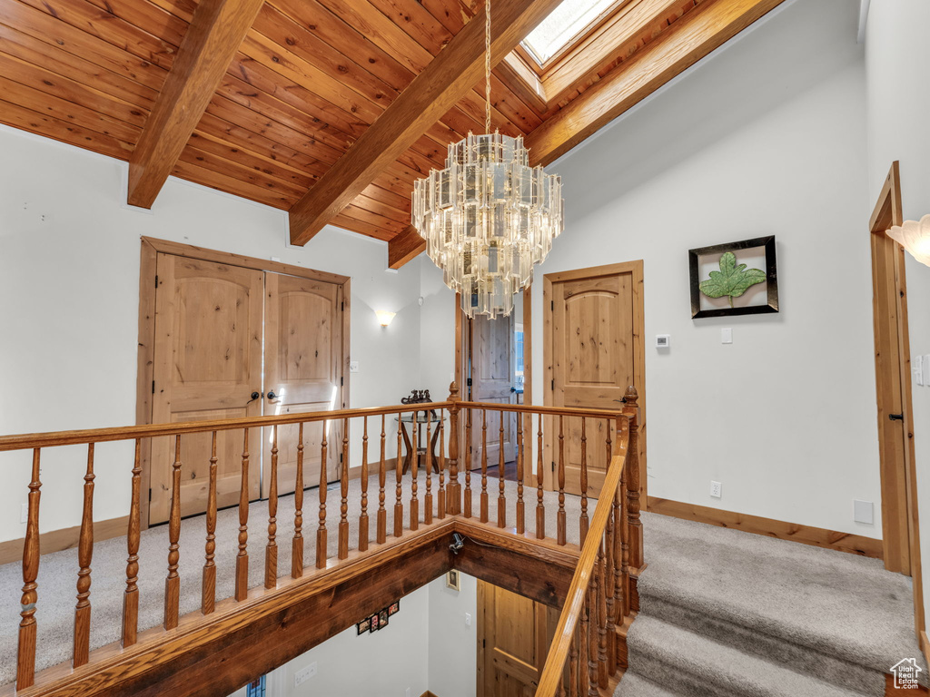 Stairway featuring carpet floors, wood ceiling, a chandelier, and a skylight