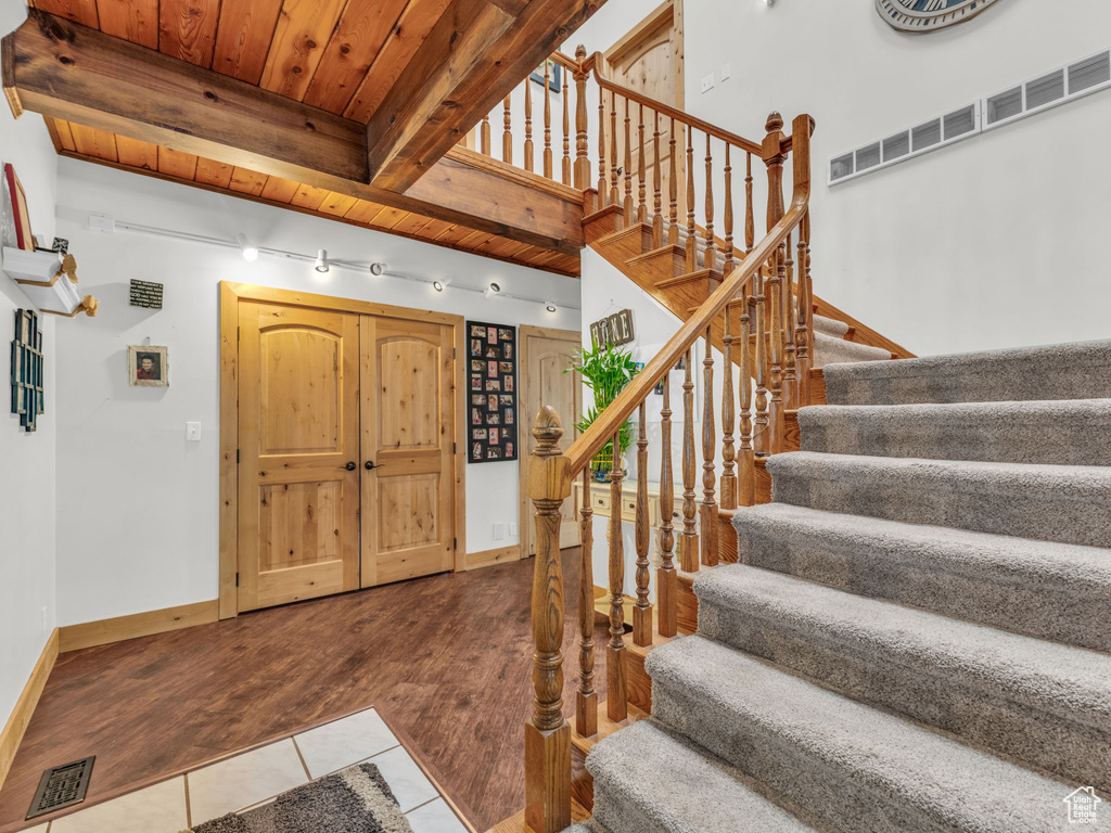Entrance foyer with tile patterned flooring, stairway, and a wood ceiling with exposed beams
