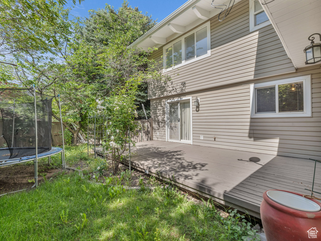 Rear view of house featuring a trampoline and a deck