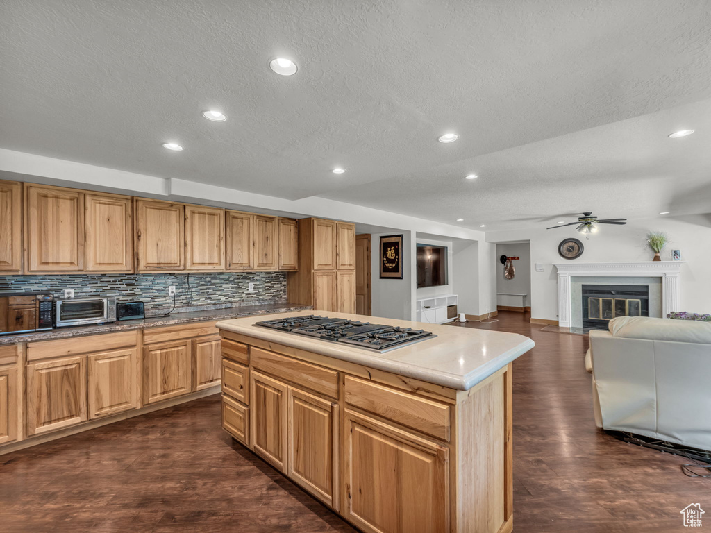 Kitchen with stainless steel gas cooktop, recessed lighting, backsplash, dark wood finished floors, and a ceiling fan