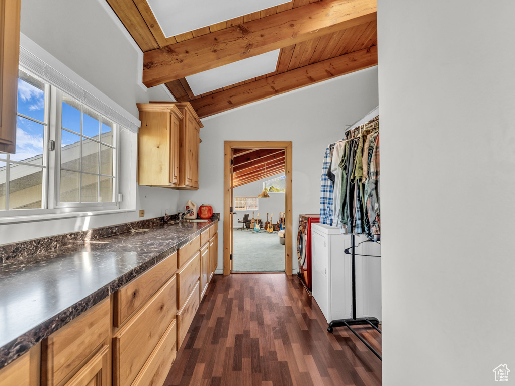 Kitchen featuring washer and clothes dryer, plenty of natural light, dark wood-type flooring, and dark countertops