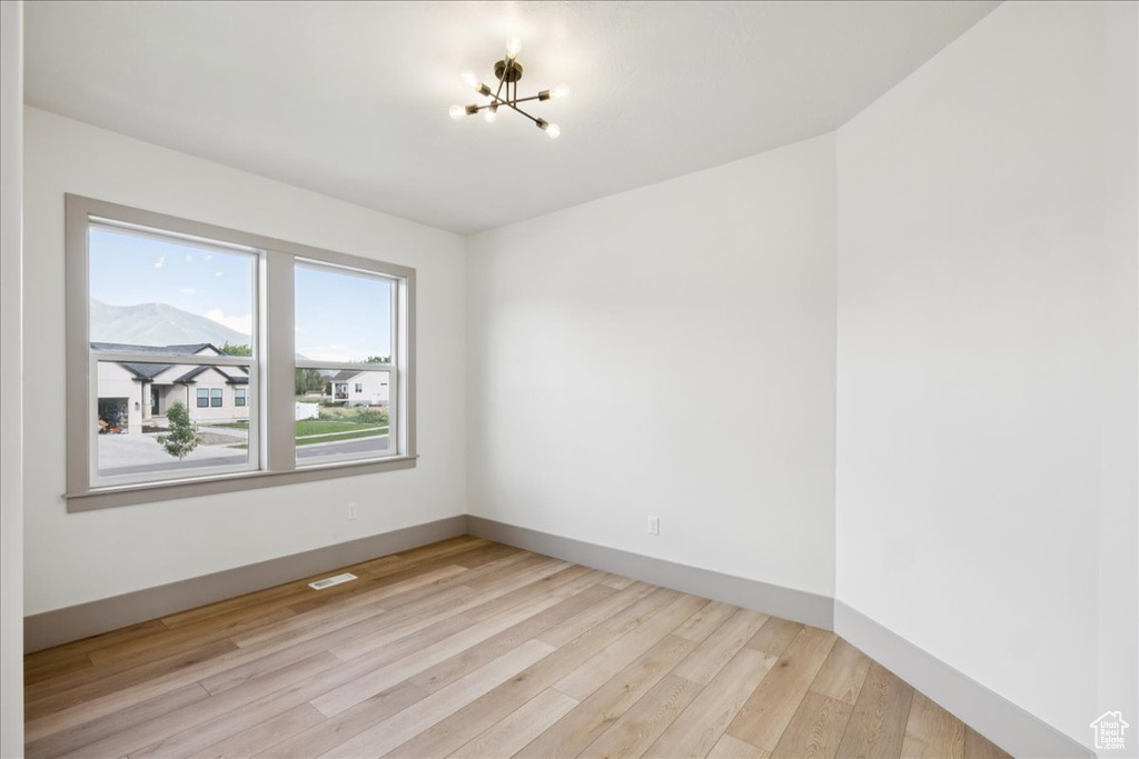 Empty room with a chandelier and light wood-style flooring