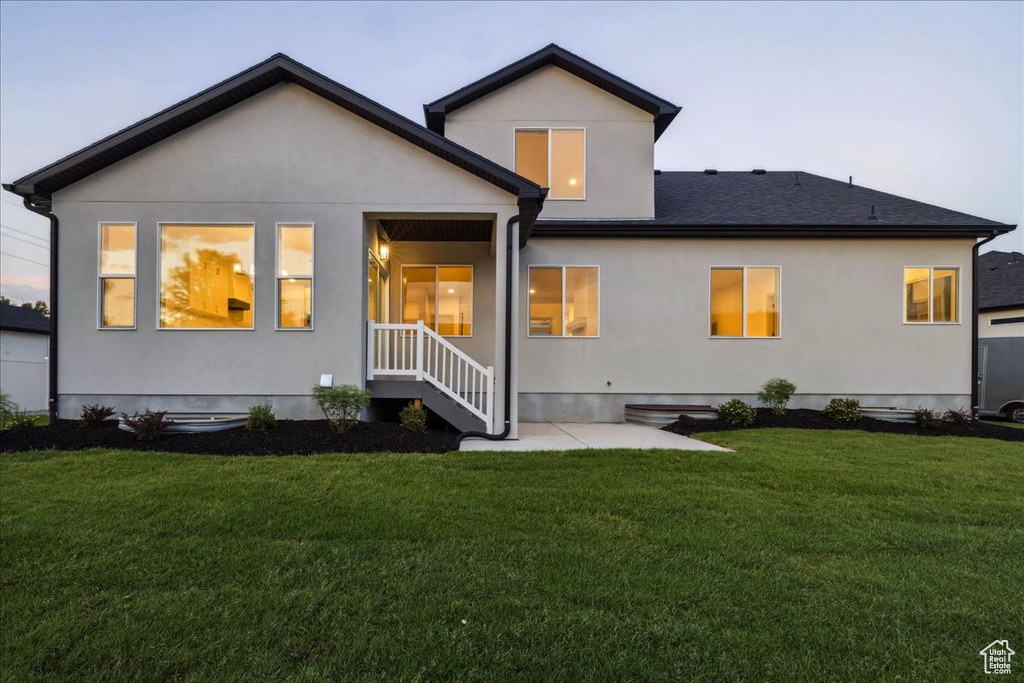 Back of property featuring a lawn, a patio, and roof with shingles