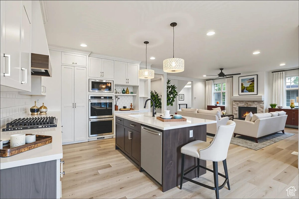 Kitchen featuring appliances with stainless steel finishes, a ceiling fan, light countertops, white cabinetry, and decorative backsplash