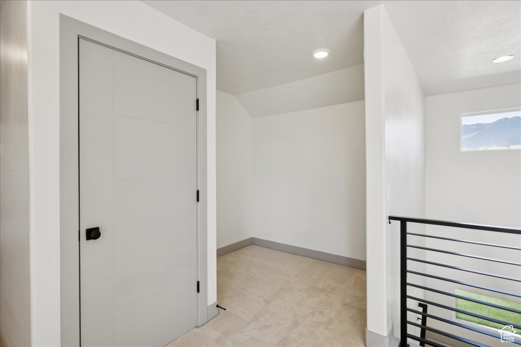 Hallway with light carpet and recessed lighting