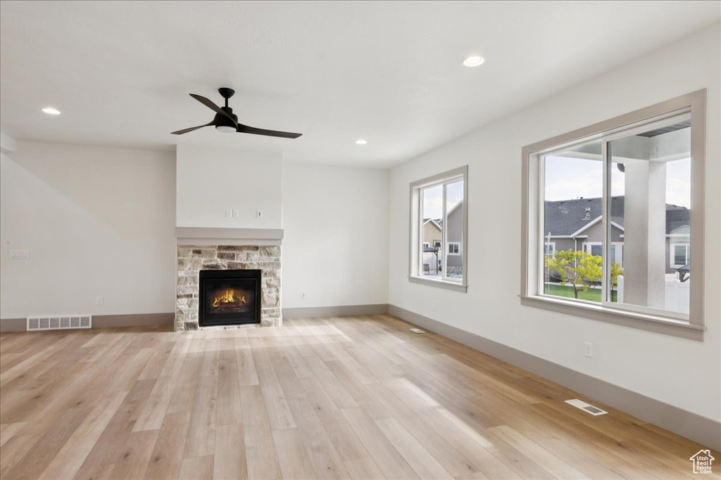 Unfurnished living room with light wood finished floors, a fireplace, a ceiling fan, and recessed lighting