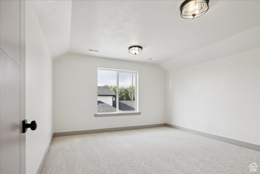 Additional living space featuring lofted ceiling and carpet