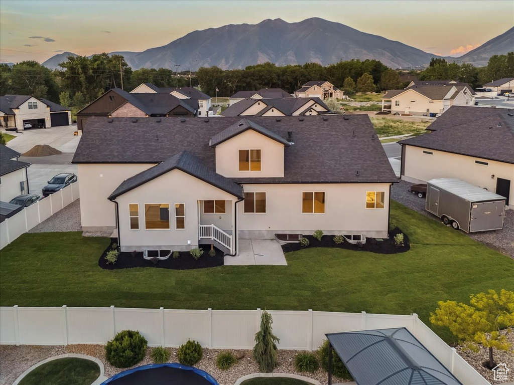 Rear view of property with a mountain view, a fenced backyard, a shingled roof, and a residential view