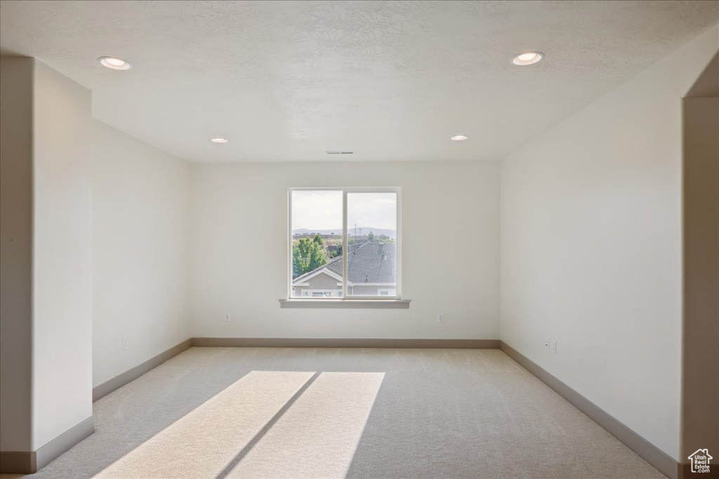 Spare room featuring light colored carpet and recessed lighting