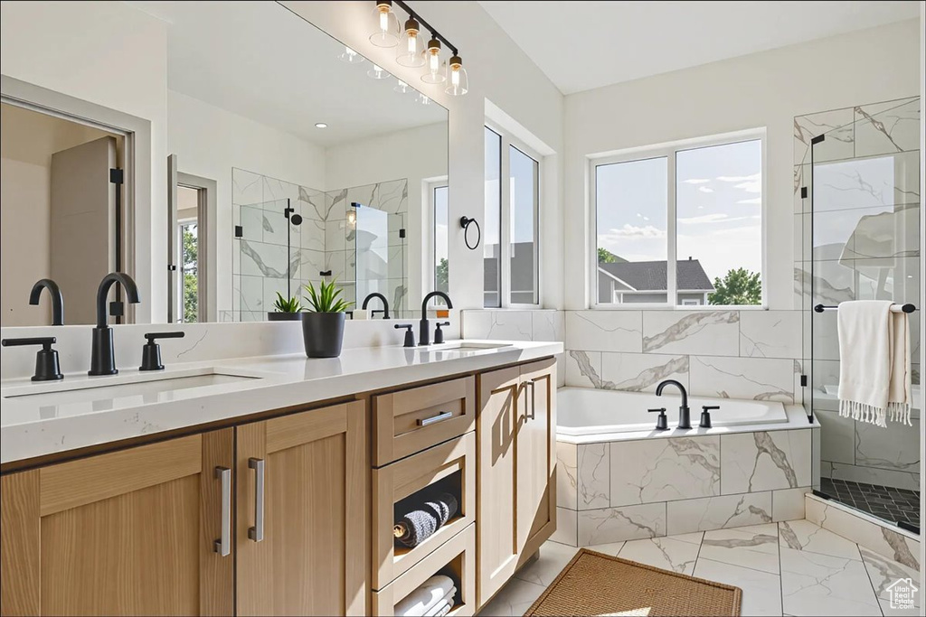 Bathroom with a marble finish shower, healthy amount of natural light, a garden tub, and double vanity