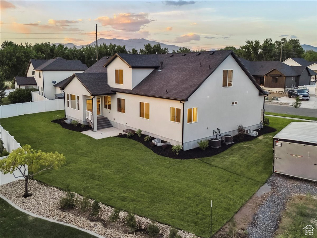Back of house at dusk featuring stucco siding, roof with shingles, and a mountain view