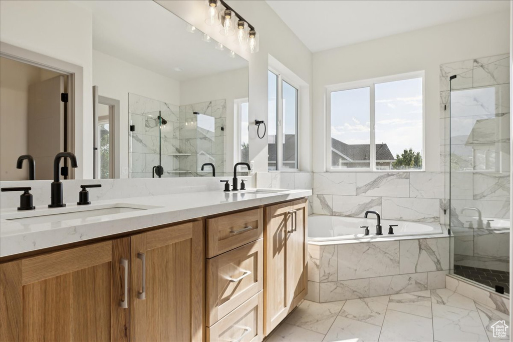 Bathroom featuring a marble finish shower, a bath, double vanity, and marble look tile flooring