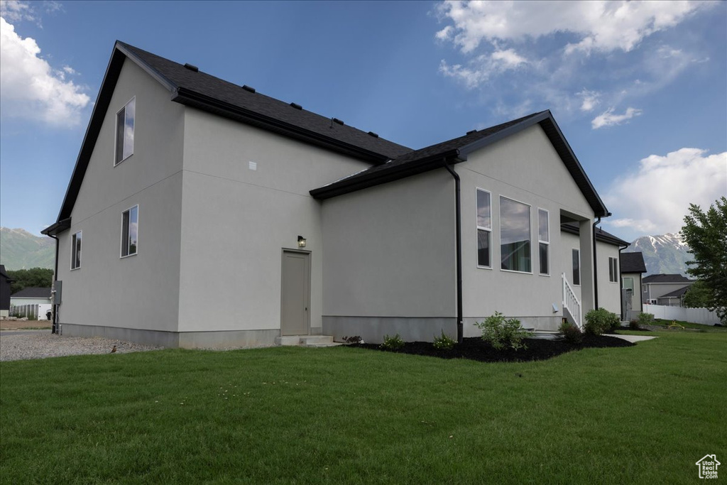 Back of house with a yard, stucco siding, and a mountain view