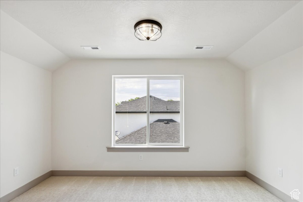 Additional living space featuring vaulted ceiling and light carpet