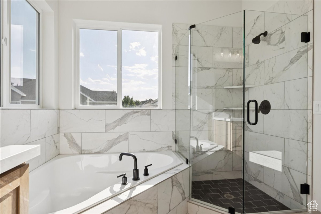 Bathroom featuring a garden tub, a marble finish shower, and healthy amount of natural light
