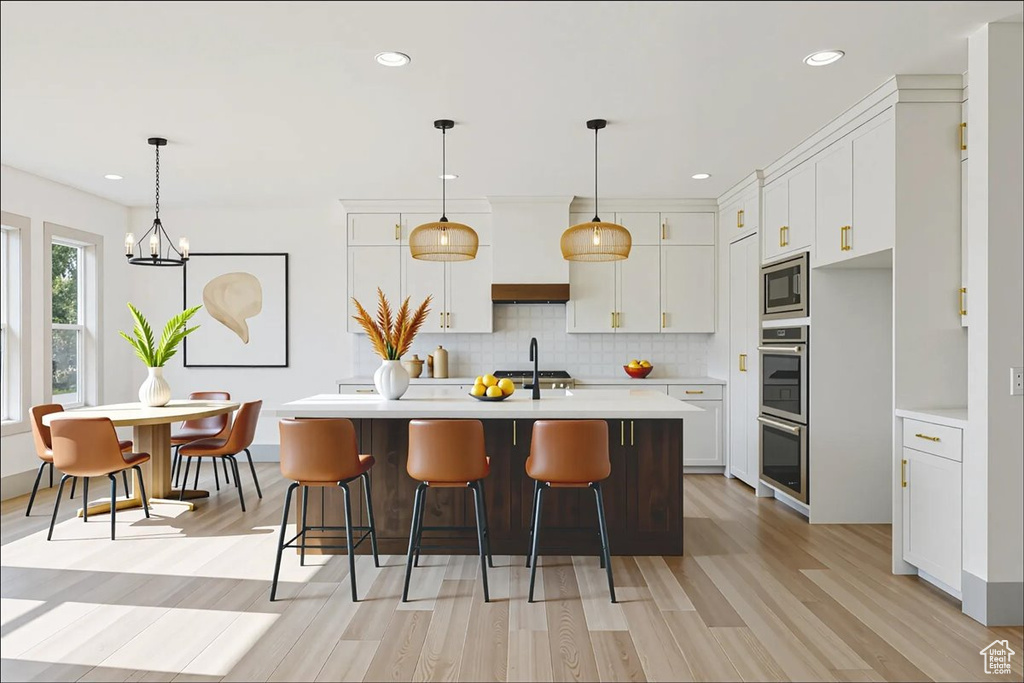 Kitchen with appliances with stainless steel finishes, light countertops, light wood-style floors, backsplash, and white cabinets