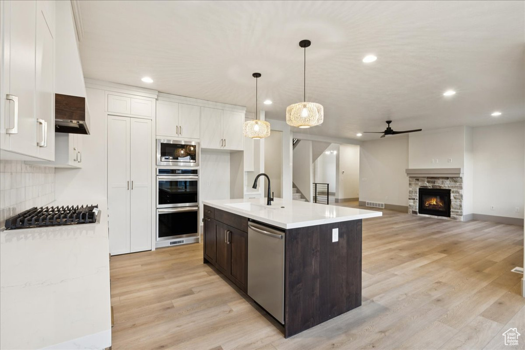 Kitchen with stainless steel appliances, ceiling fan, dark brown cabinets, light countertops, and white cabinets