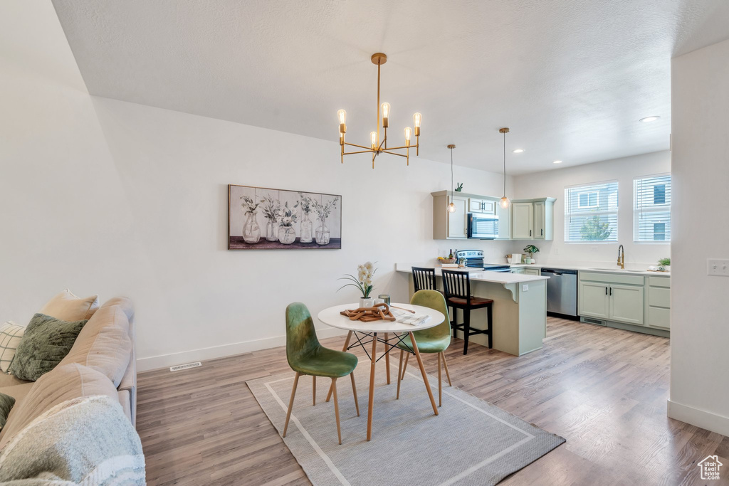 Dining space with a chandelier, light wood-type flooring, and recessed lighting