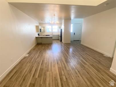 Unfurnished living room featuring wood finished floors and a chandelier