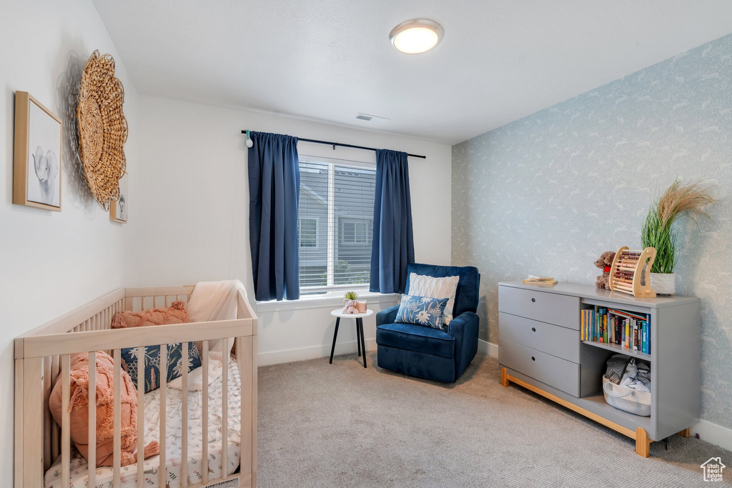 Bedroom with a crib and carpet flooring