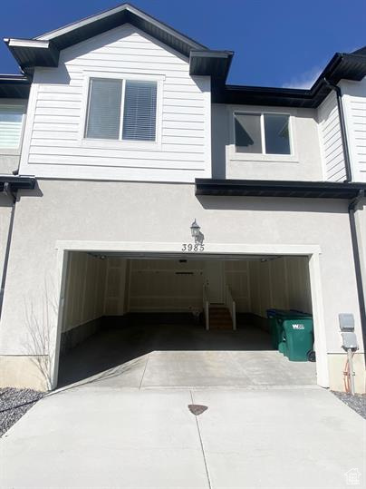 View of side of home featuring stucco siding, an attached garage, and driveway
